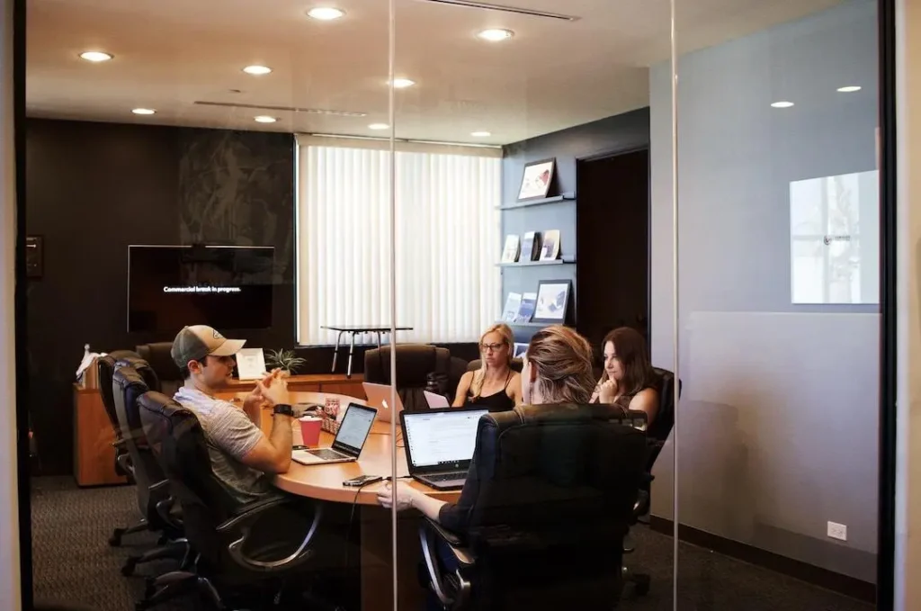 A team sitting at a conference table with laptops discussing the benefits of leveraging resource forecasting