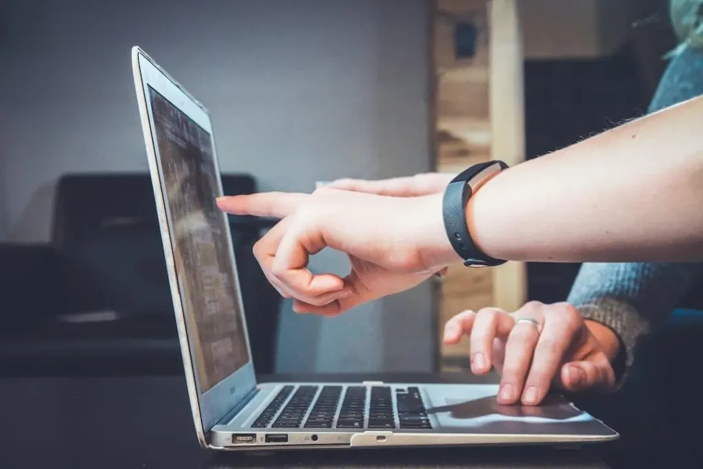 Two people point at a laptop screen, discussing leveraging resource forecasting